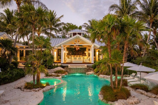 pool at dusk with an outdoor living space, an in ground hot tub, ceiling fan, and a patio