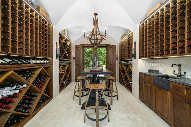 wine room featuring lofted ceiling, sink, and an inviting chandelier