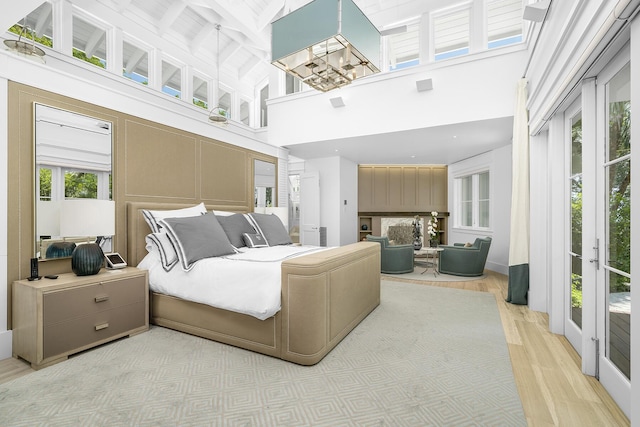 bedroom featuring a towering ceiling, light hardwood / wood-style floors, and a notable chandelier