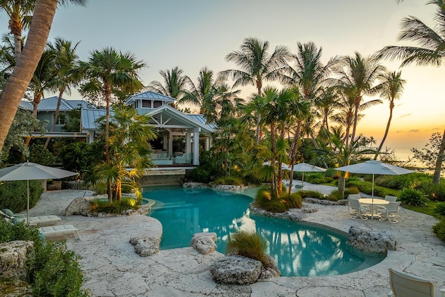 pool at dusk featuring a patio area