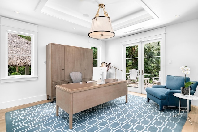 office area with french doors, a healthy amount of sunlight, a tray ceiling, and hardwood / wood-style flooring