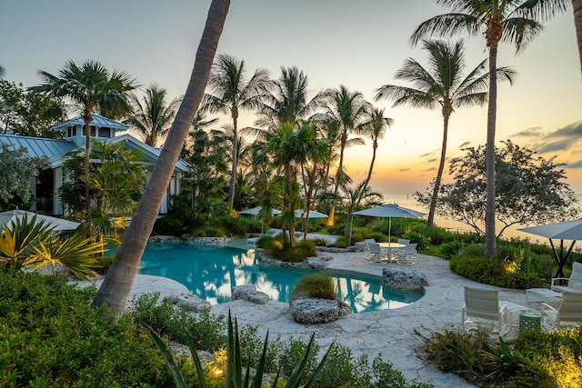 pool at dusk featuring a patio