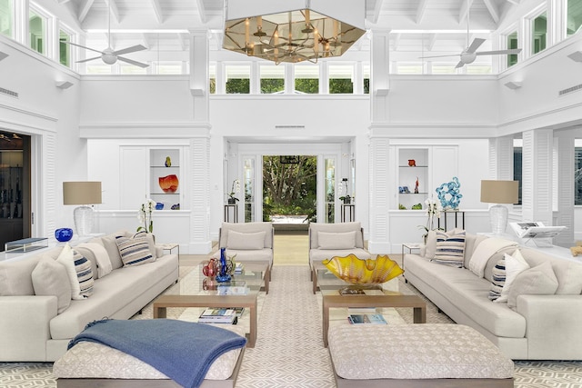 living room with beamed ceiling, a towering ceiling, and ceiling fan with notable chandelier