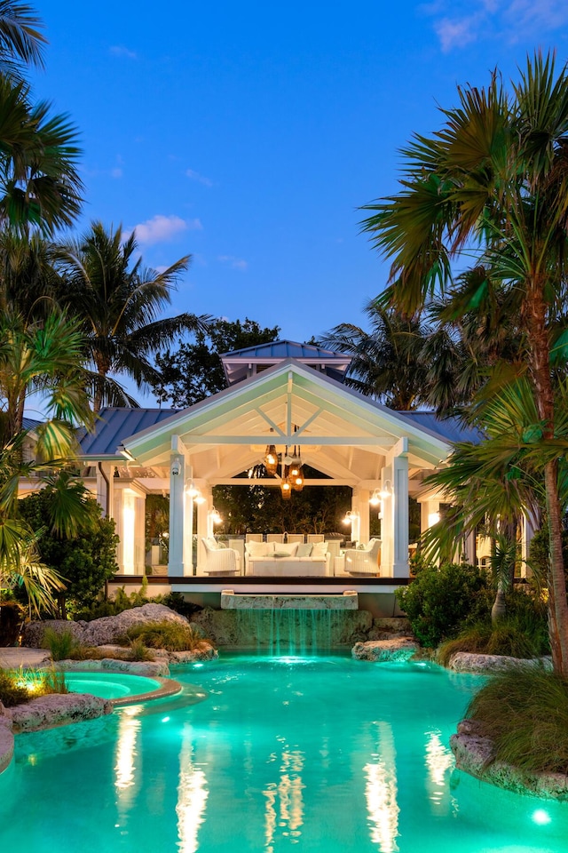 pool at dusk with an outdoor structure and ceiling fan