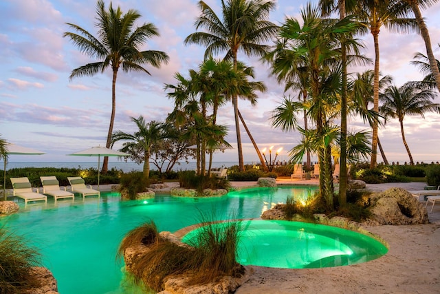 pool at dusk with an in ground hot tub