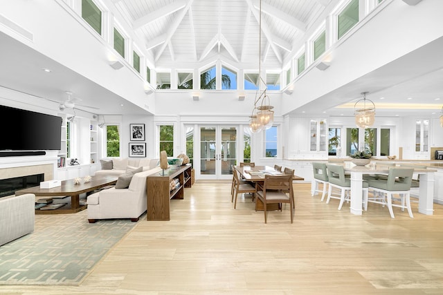 living room with beam ceiling, a chandelier, light wood-type flooring, and french doors