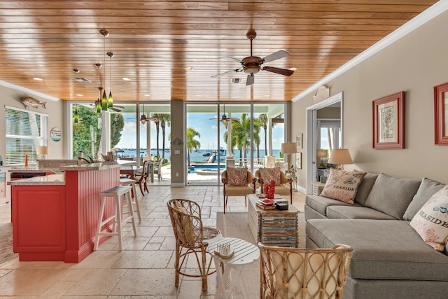 living area featuring stone tile floors, wood ceiling, crown molding, and ceiling fan