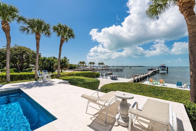 outdoor pool with a water view, a dock, and a patio area