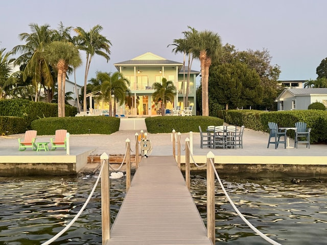 view of dock with a patio, a balcony, and a water view