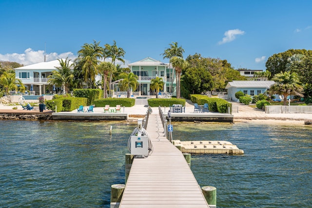 view of dock with a water view, fence, a balcony, and a patio area