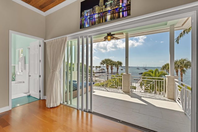 doorway with a water view, wood finished floors, and crown molding