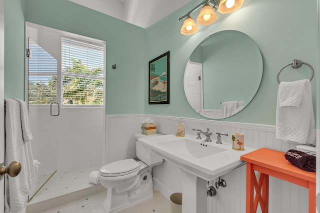 full bath with tile patterned flooring, a wainscoted wall, a shower stall, and toilet