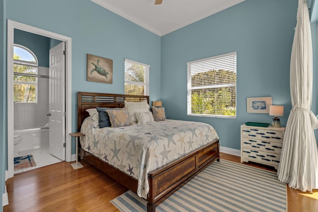 bedroom featuring ornamental molding, wood finished floors, connected bathroom, baseboards, and ceiling fan