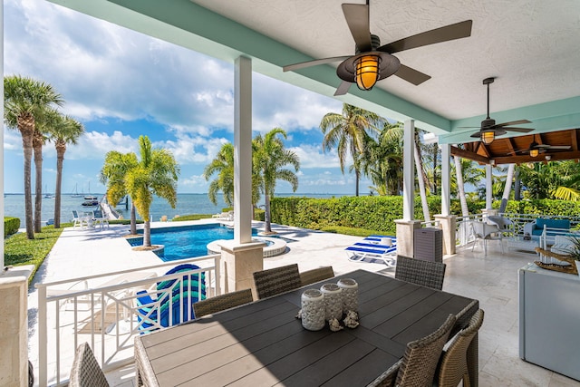 view of patio / terrace featuring an outdoor pool, outdoor dining area, a water view, and a ceiling fan