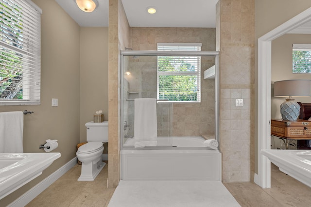 full bath featuring tile patterned flooring, a healthy amount of sunlight, toilet, and shower / bath combination with glass door