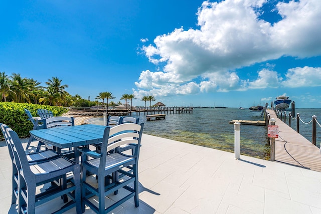 view of patio featuring outdoor dining area, a water view, and a boat dock