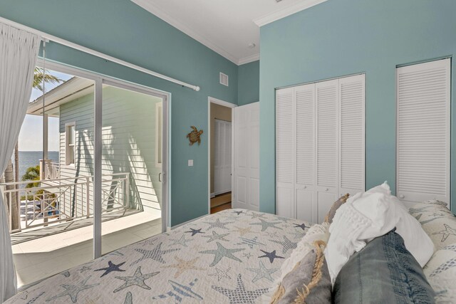 bedroom featuring visible vents, a baseboard radiator, a water view, crown molding, and two closets