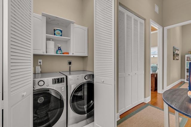 washroom with baseboards, cabinet space, light wood-style floors, and independent washer and dryer