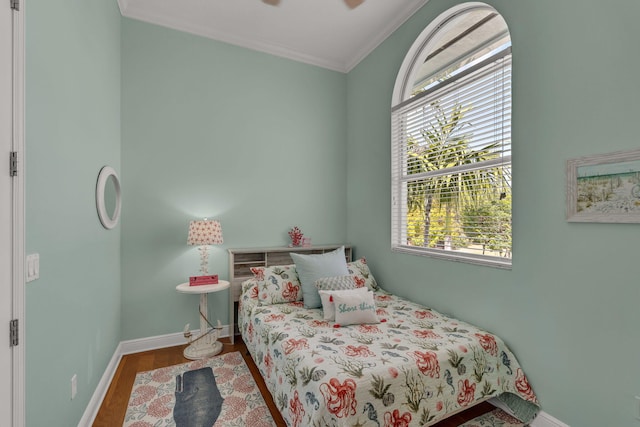 bedroom with baseboards, wood finished floors, and ornamental molding