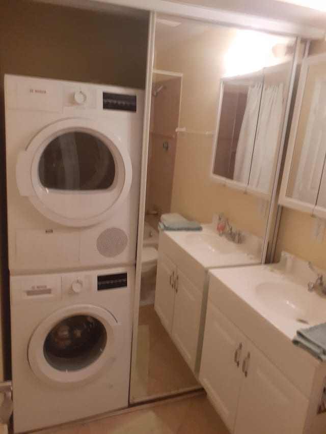 washroom featuring stacked washer and dryer, sink, and light tile patterned flooring