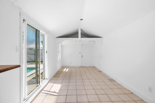 empty room with light tile patterned flooring, baseboards, and lofted ceiling