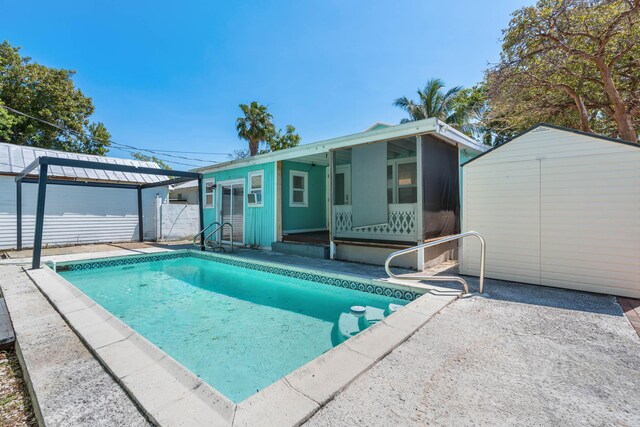 back of property featuring an outbuilding, a patio, fence, a storage shed, and an outdoor pool