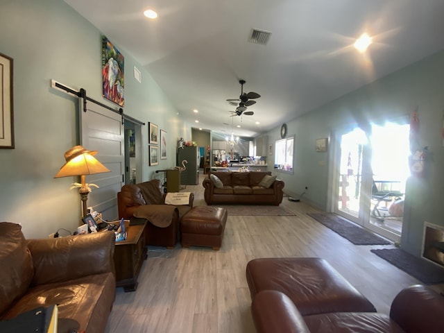 living room featuring a barn door, a ceiling fan, light wood-style floors, recessed lighting, and vaulted ceiling