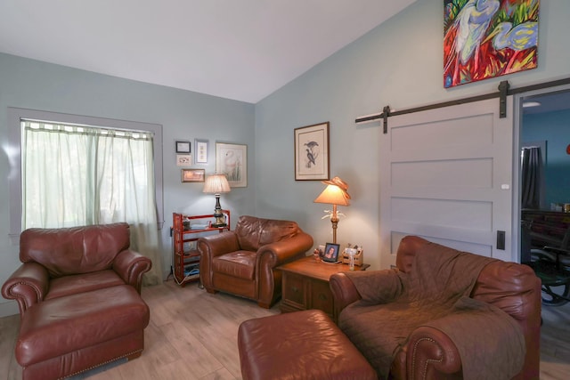 living area with a barn door, light wood-style flooring, and lofted ceiling