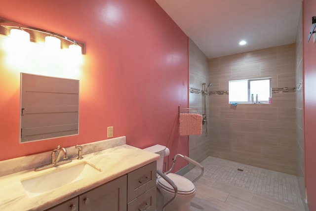 full bathroom with toilet, tiled shower, vanity, and recessed lighting