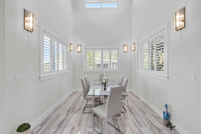 dining area featuring a high ceiling and baseboards