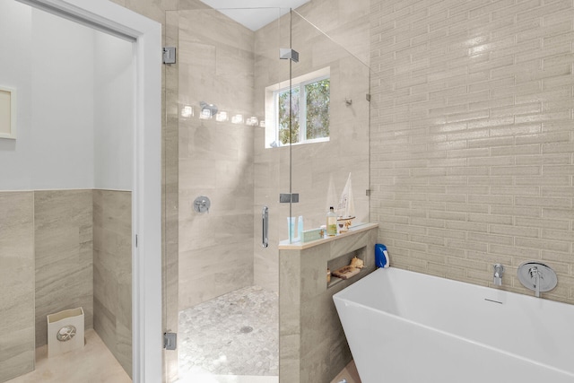 bathroom with a stall shower, tile walls, and a soaking tub