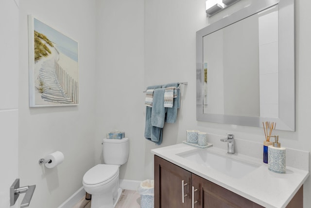 bathroom with toilet, baseboards, and vanity