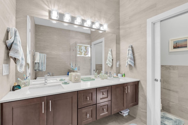 full bathroom featuring a sink, tile walls, a shower stall, and double vanity