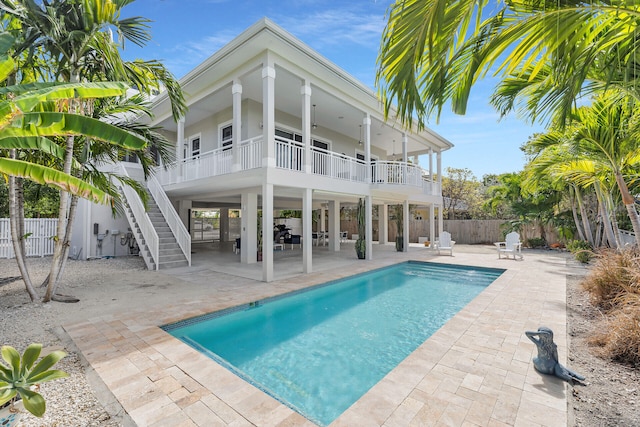 back of house featuring a fenced backyard, a balcony, stairway, a fenced in pool, and a patio area