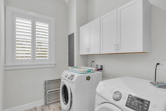 laundry room featuring cabinet space, electric panel, baseboards, and washing machine and clothes dryer