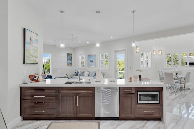 kitchen featuring appliances with stainless steel finishes, open floor plan, a sink, and light countertops