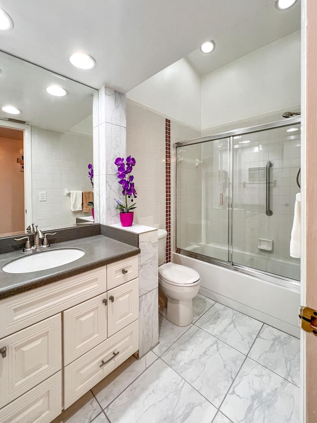 full bathroom with enclosed tub / shower combo, vanity, and toilet