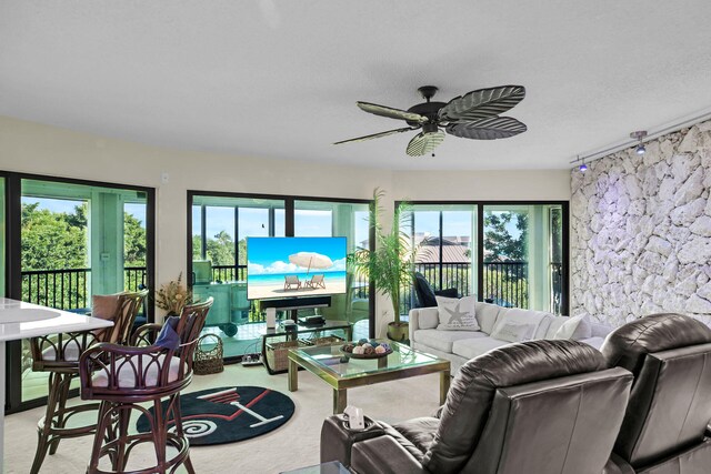 living room featuring ceiling fan, light colored carpet, rail lighting, and a healthy amount of sunlight