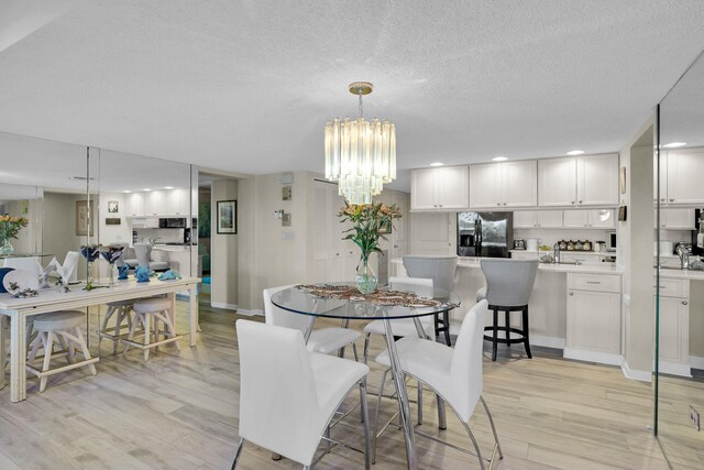 dining space featuring an inviting chandelier, a textured ceiling, and light wood-type flooring