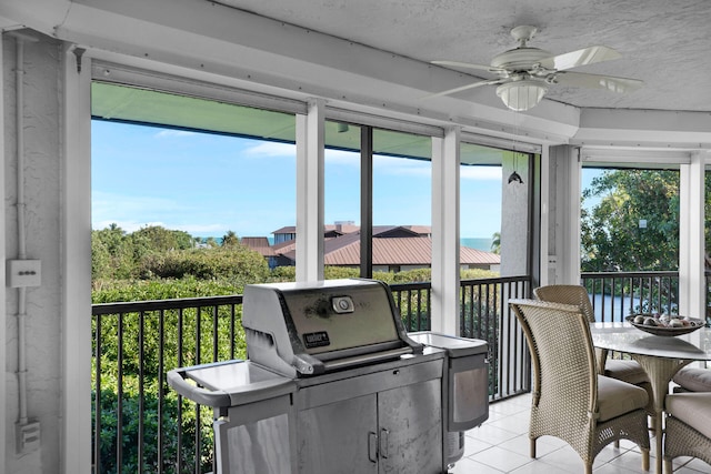 sunroom featuring ceiling fan and a water view