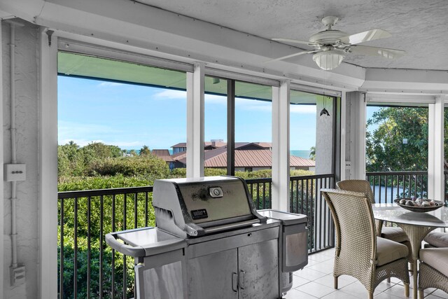sunroom featuring ceiling fan and a water view