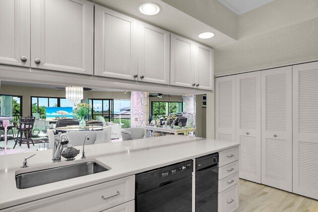 kitchen featuring white cabinetry, black dishwasher, sink, and light hardwood / wood-style floors