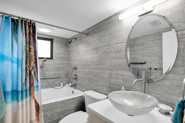 full bathroom with toilet, tile walls, vanity, and shower / bath combo with shower curtain