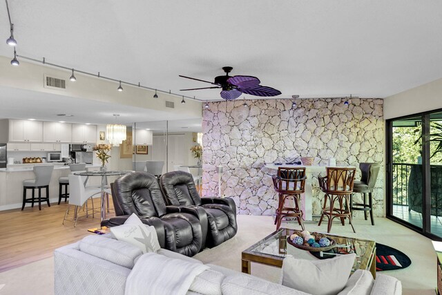 living room featuring ceiling fan with notable chandelier and light hardwood / wood-style flooring