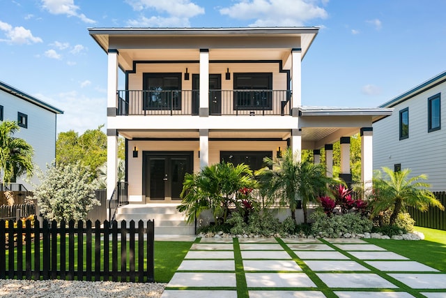 view of front of property with a fenced front yard, covered porch, and a balcony