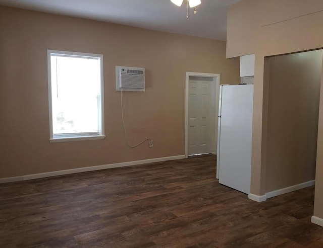 spare room with baseboards, a wall unit AC, a ceiling fan, and dark wood finished floors