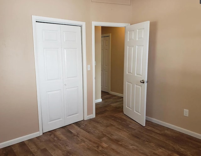 unfurnished bedroom with a closet, baseboards, and dark wood finished floors