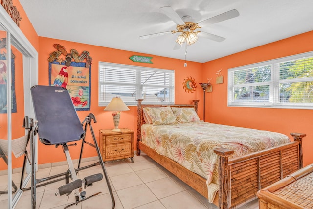 bedroom featuring a ceiling fan, multiple windows, baseboards, and light tile patterned floors