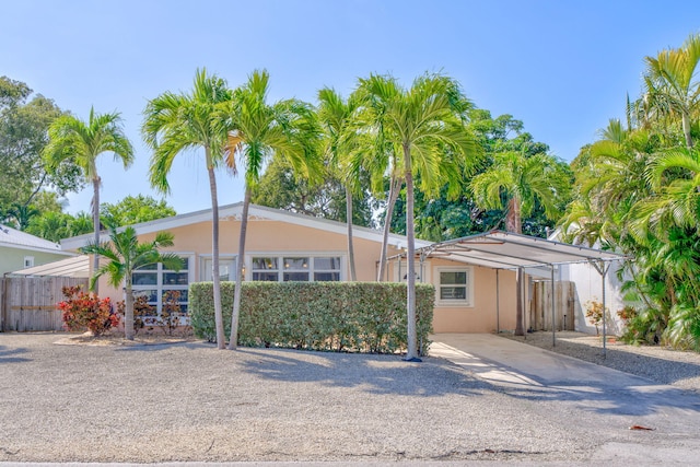 view of front of property featuring stucco siding, fence, and a carport