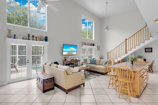 living room with a towering ceiling, french doors, ceiling fan, and light tile patterned flooring